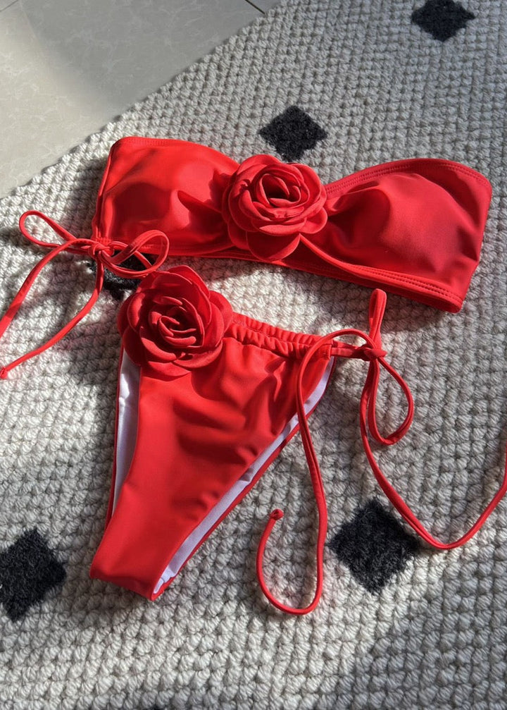 Red bikini set with floral designs on a textured surface