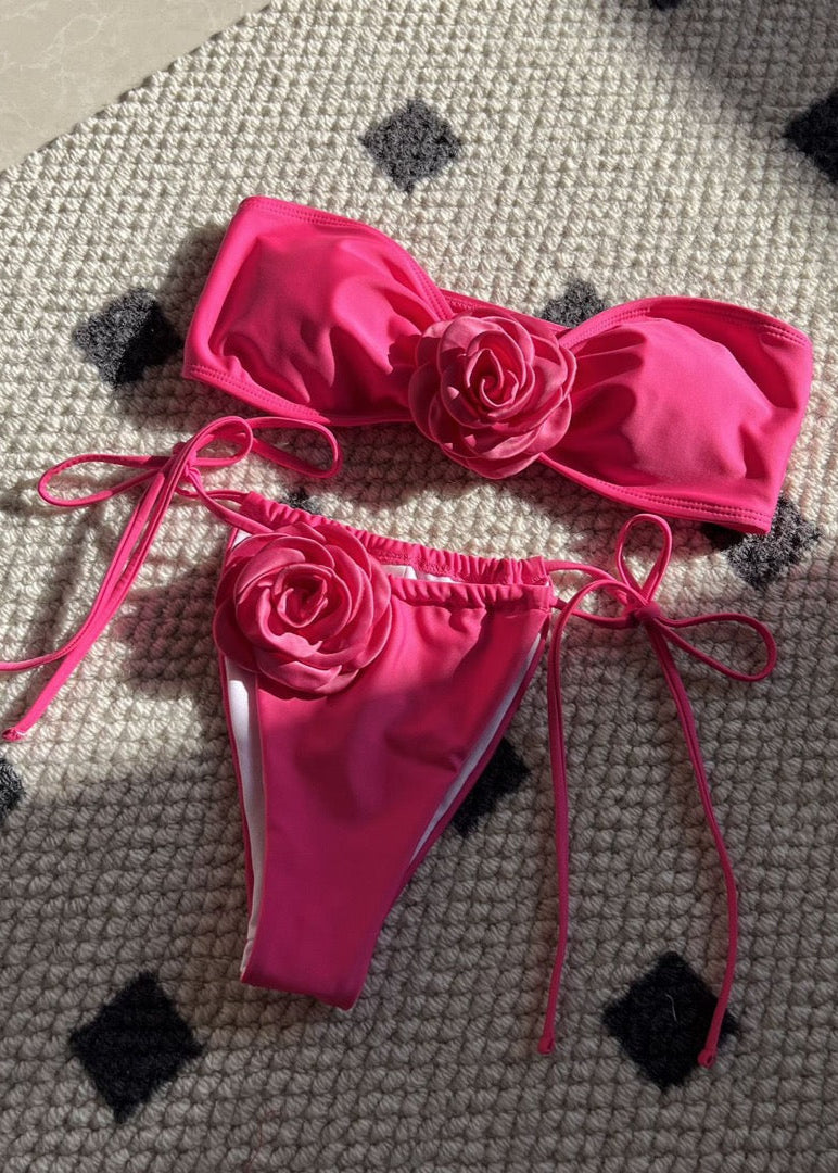 Pink bikini set with floral designs on a textured surface