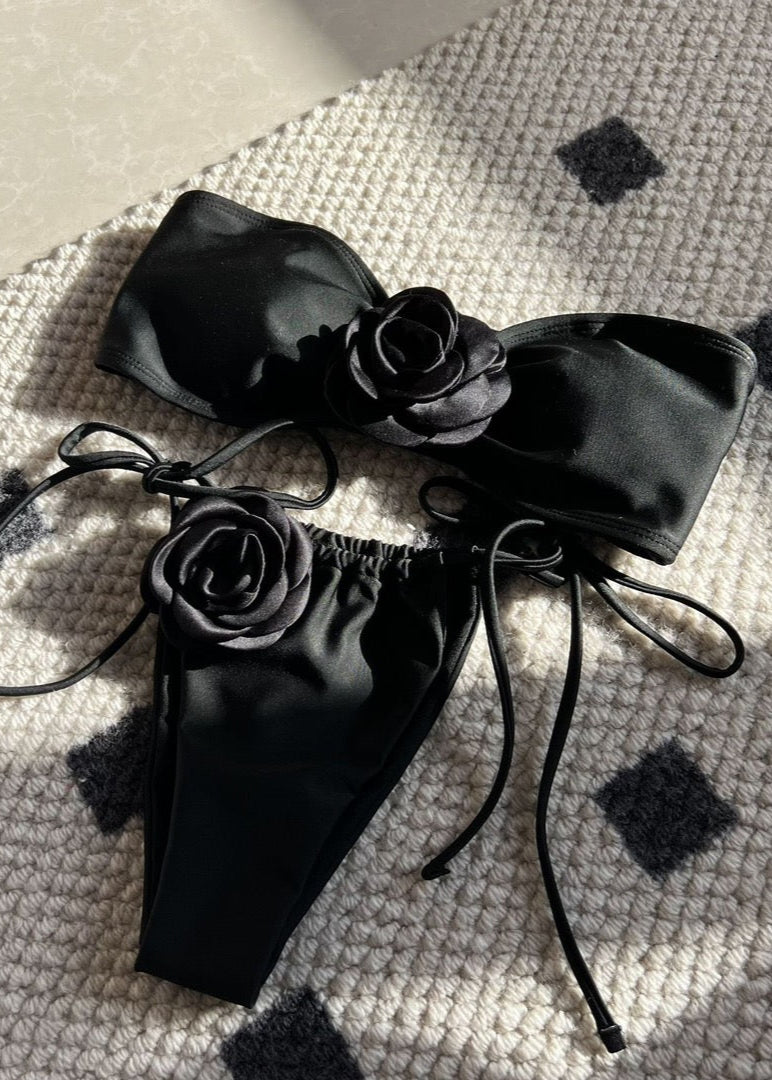 Black satin lingerie set with floral details on a textured surface