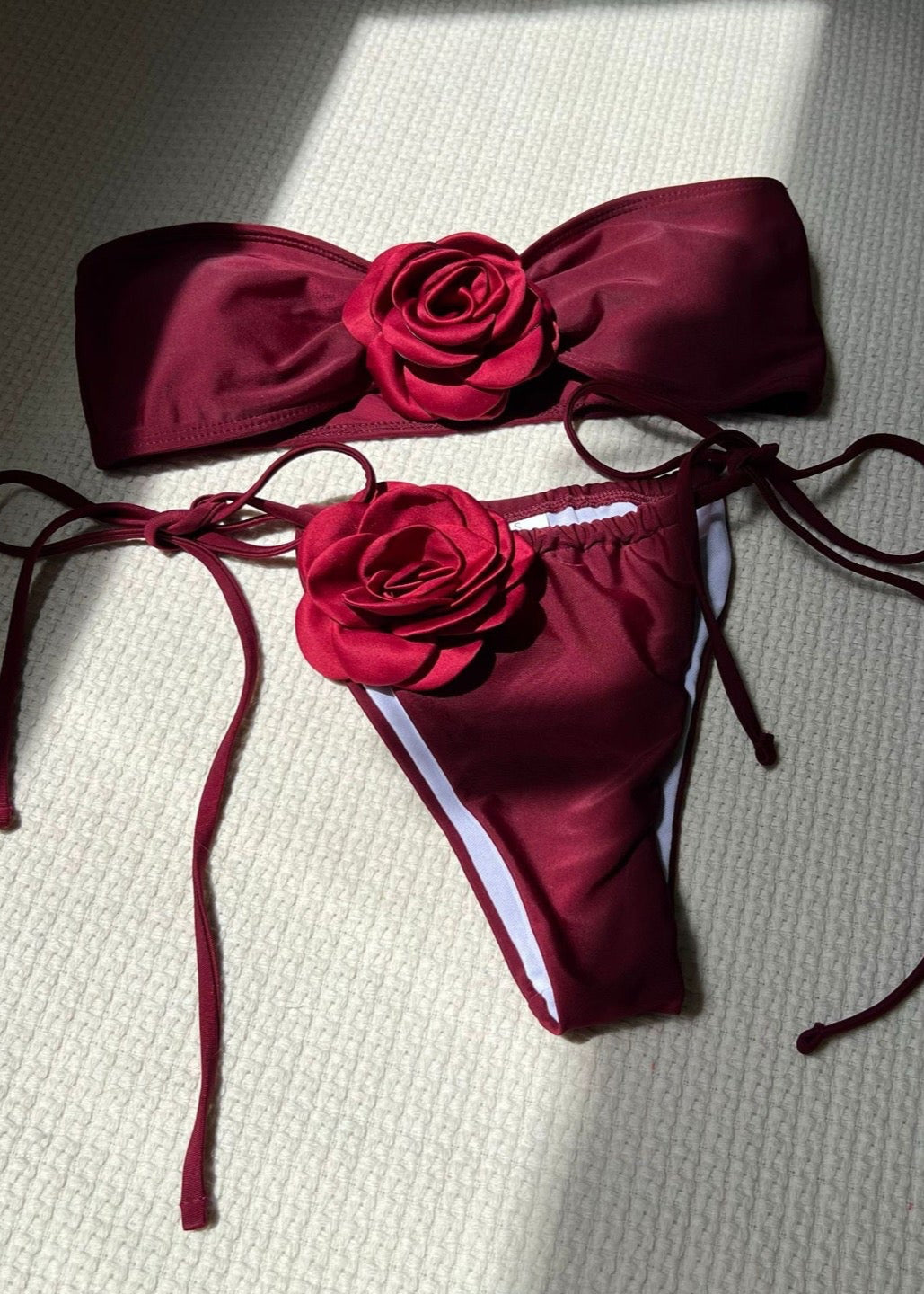 Red bikini set with floral details on a textured surface