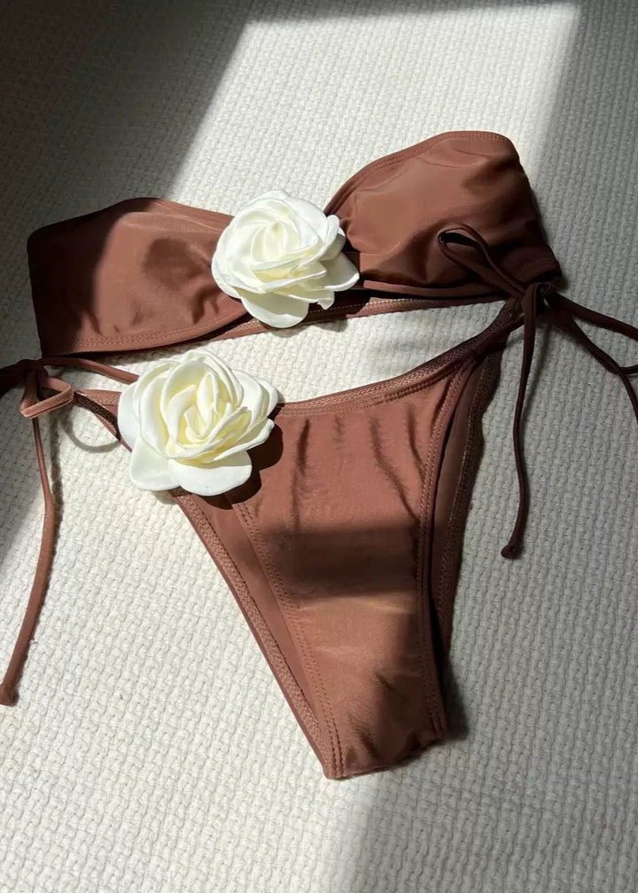 Brown bikini set with white flowers on a textured surface