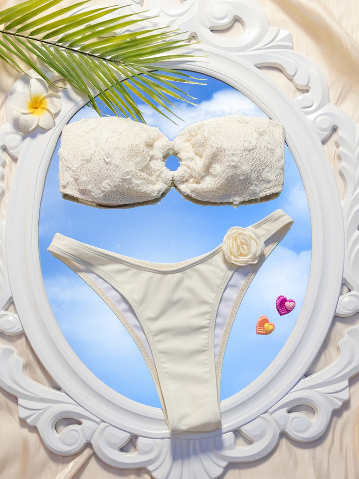 White bikini set with decorative elements on a decorative frame with palm leaf and flowers.