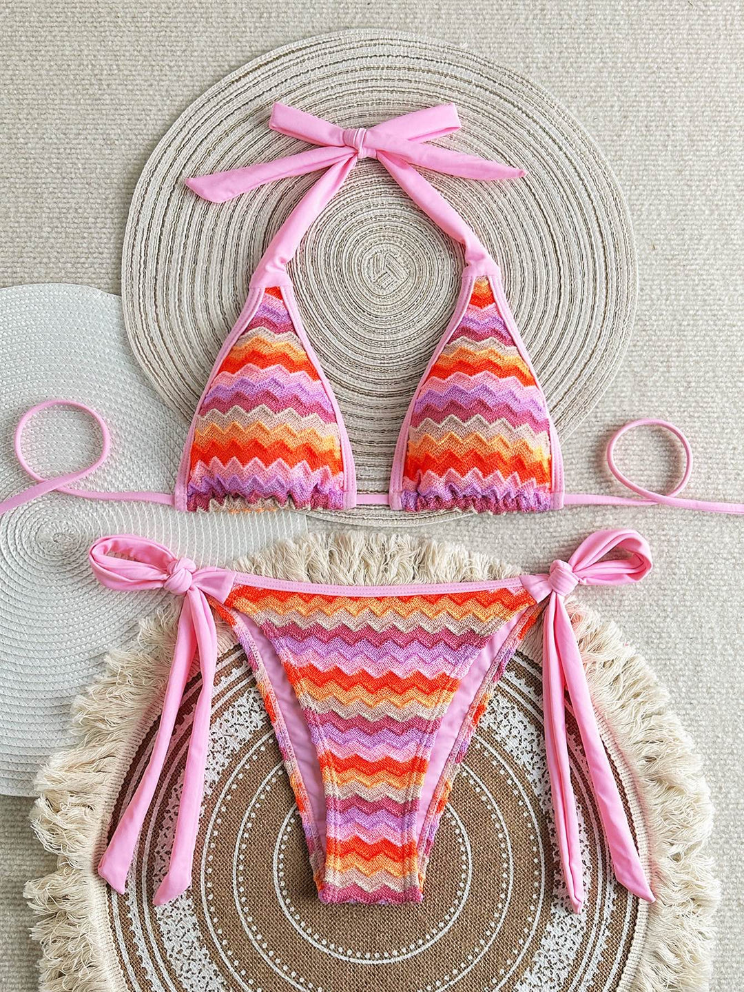 Colorful striped bikini set with pink straps on a textured surface